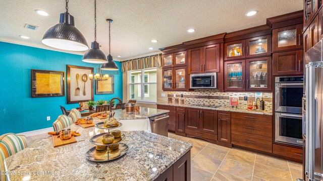 2683 Amati Dr, Kissimmee, FL 34741 - kitchen featuring stainless steel appliances, an island with sink, ornamental molding, pendant lighting, and recessed lighting