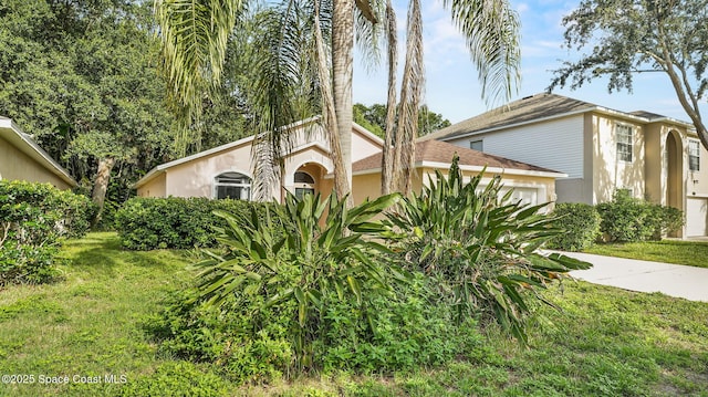 1119 Macon Dr, Titusville, FL 32780 - view of front of home featuring an attached garage, concrete driveway, a front yard, and stucco siding