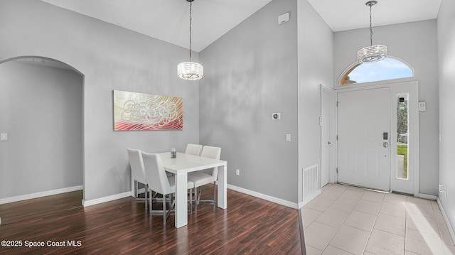 1119 Macon Dr, Titusville, FL 32780 - dining room featuring high vaulted ceiling, a chandelier, wood finished floors, and arched walkways