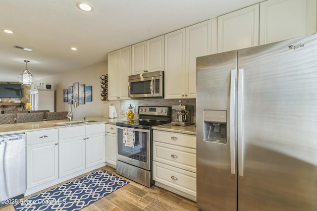 57 Broad St Unit 6, Titusville, FL 32796 - kitchen with appliances with stainless steel finishes, backsplash, light wood finished floors, recessed lighting, and white cabinets