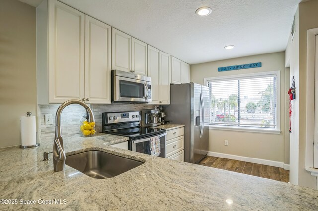 57 Broad St Unit 6, Titusville, FL 32796 - kitchen featuring appliances with stainless steel finishes, decorative backsplash, light stone countertops, a textured ceiling, and white cabinets