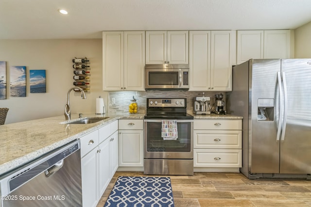 57 Broad St Unit 6, Titusville, FL 32796 - kitchen with appliances with stainless steel finishes, decorative backsplash, light stone counters, light wood-style flooring, and white cabinets