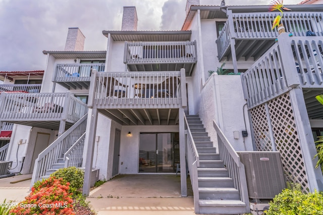 57 Broad St Unit 6, Titusville, FL 32796 - rear view of house featuring stairway, stucco siding, a chimney, and a patio area