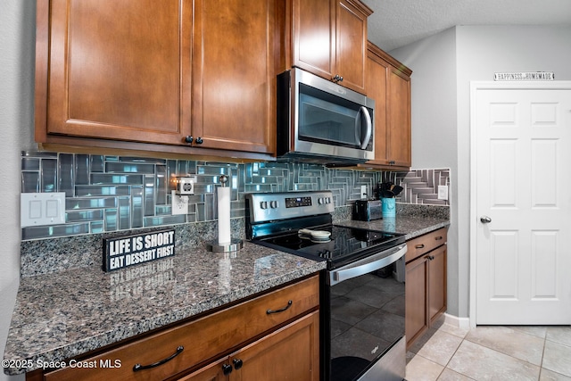 820 Old Country Rd SE, Palm Bay, FL 32909 - kitchen featuring stainless steel appliances, decorative backsplash, brown cabinets, dark stone countertops, and light tile patterned floors