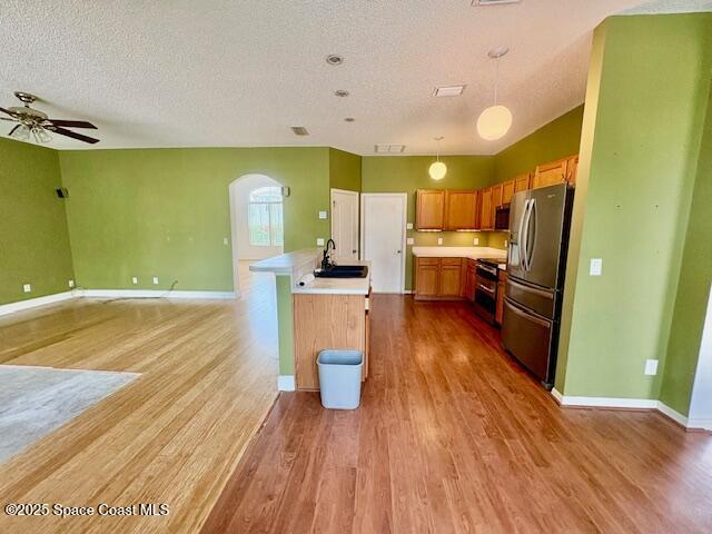 968 Shaw Cir, Melbourne, FL 32940 - kitchen featuring stainless steel appliances, a textured ceiling, light countertops, light wood finished floors, and open floor plan