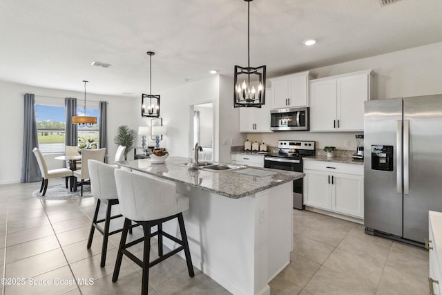 1669 Mineral Loop Dr NW, Palm Bay, FL 32907 - kitchen with a chandelier, stainless steel appliances, light stone countertops, white cabinetry, and a center island with sink