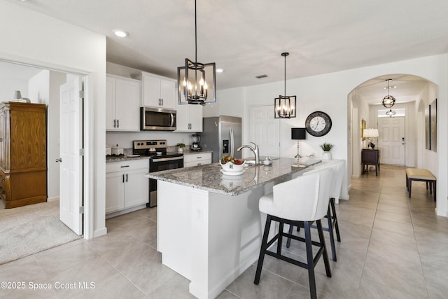 1669 Mineral Loop Dr NW, Palm Bay, FL 32907 - kitchen featuring stainless steel appliances, arched walkways, a chandelier, light tile patterned floors, and white cabinetry