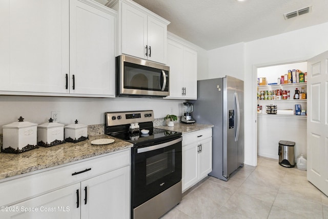 1669 Mineral Loop Dr NW, Palm Bay, FL 32907 - kitchen with stainless steel appliances, white cabinets, light stone counters, and light tile patterned floors
