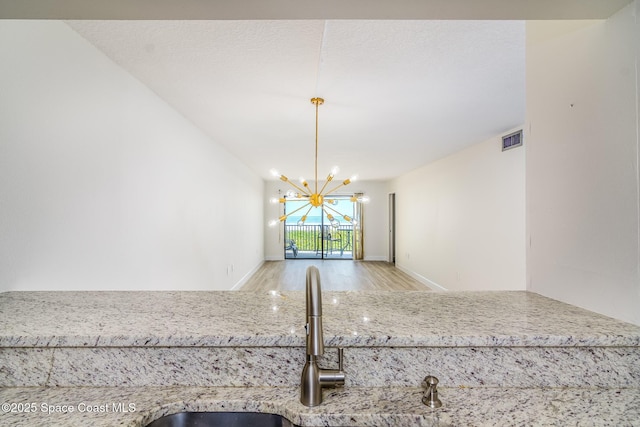 8496 Ridgewood Ave Unit 3205, Cape Canaveral, FL 32920 - kitchen with wood finished floors, a chandelier, and light stone counters
