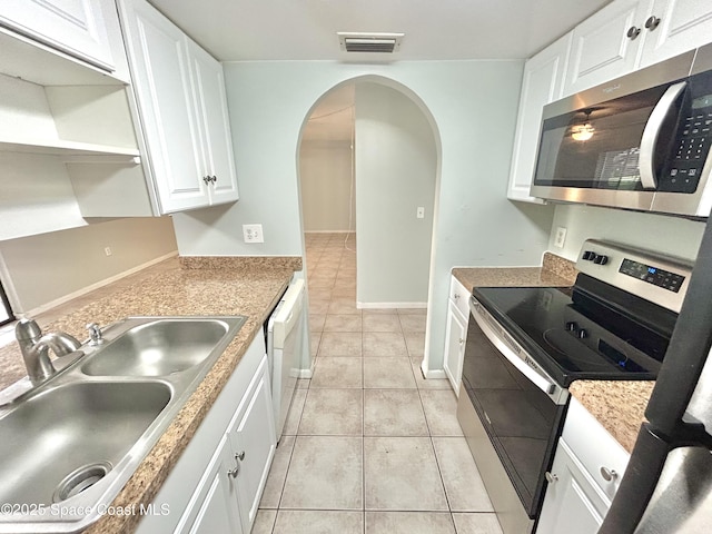 176 San Juan Cir, Melbourne, FL 32935 - kitchen featuring appliances with stainless steel finishes, arched walkways, white cabinetry, light tile patterned flooring, and open shelves