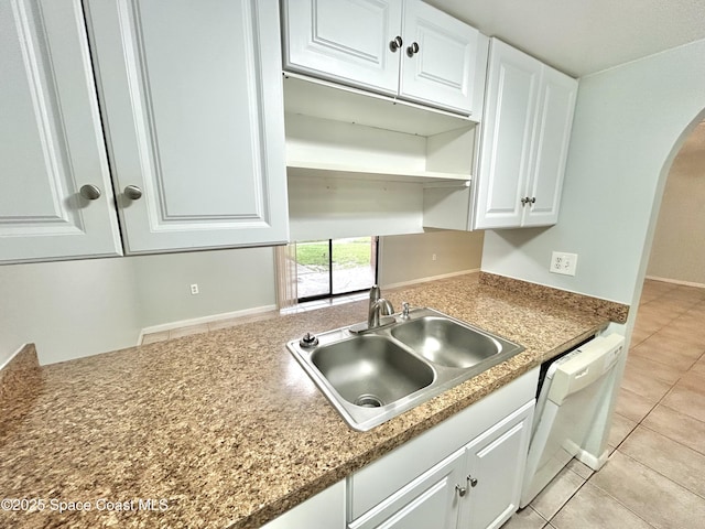 176 San Juan Cir, Melbourne, FL 32935 - kitchen with white dishwasher, arched walkways, light tile patterned floors, white cabinetry, and open shelves