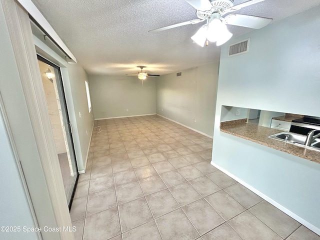 176 San Juan Cir, Melbourne, FL 32935 - unfurnished living room with a ceiling fan, a textured ceiling, and light tile patterned floors