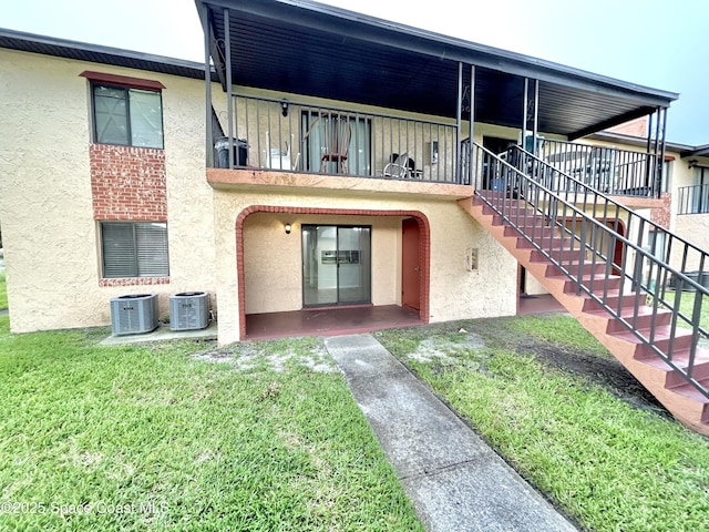 176 San Juan Cir, Melbourne, FL 32935 - rear view of property featuring stucco siding, a lawn, a patio, and stairs