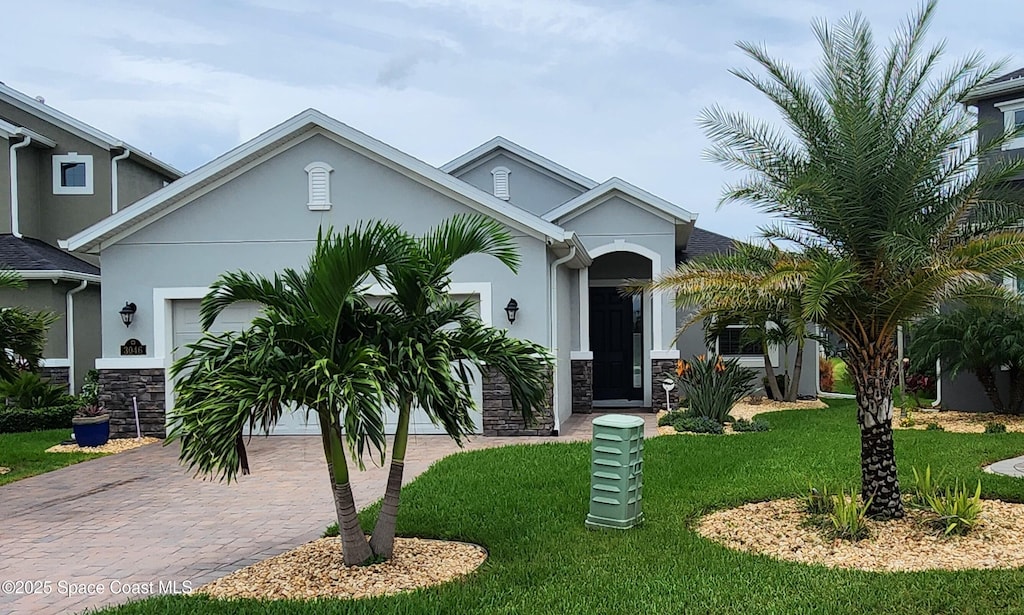 3046 Illuminate Pl, Melbourne, FL 32940 - view of front facade featuring a garage, stone siding, decorative driveway, and a front lawn