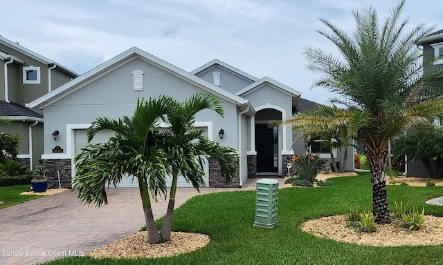 3046 Illuminate Pl, Melbourne, FL 32940 - view of front facade featuring a garage, stone siding, decorative driveway, and a front lawn