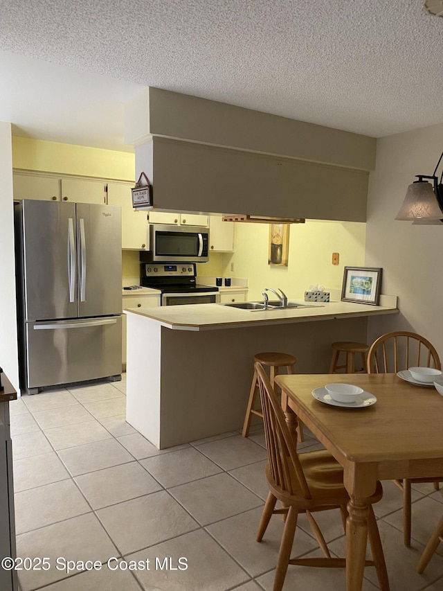 3343 Sandy Reef Ct, Melbourne Beach, FL 32951 - kitchen featuring stainless steel appliances, a peninsula, a textured ceiling, light tile patterned floors, and light countertops
