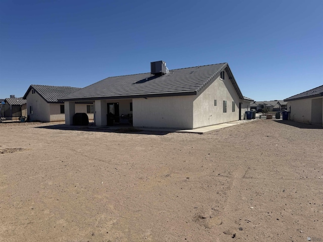 back of property with a tile roof, cooling unit, and stucco siding