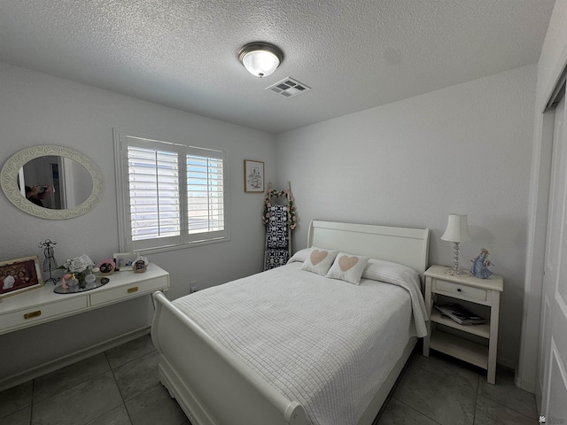 tiled bedroom with visible vents and a textured ceiling