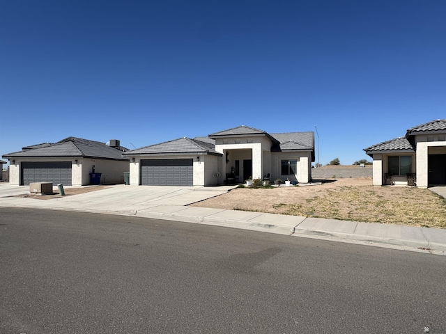 view of front of property featuring a garage, driveway, a tiled roof, and stucco siding