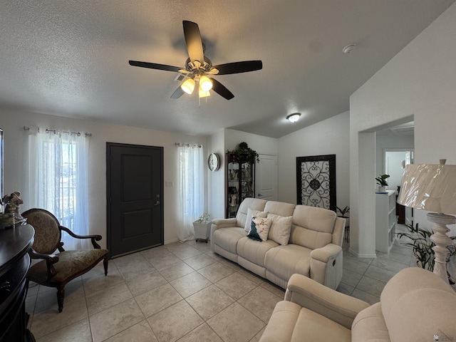 living room featuring lofted ceiling, light tile patterned flooring, ceiling fan, and a textured ceiling