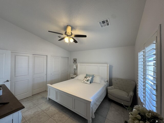 bedroom with lofted ceiling, two closets, visible vents, and a ceiling fan