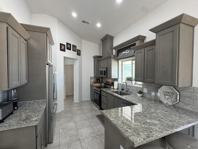 kitchen with a peninsula, a sink, visible vents, appliances with stainless steel finishes, and light stone countertops