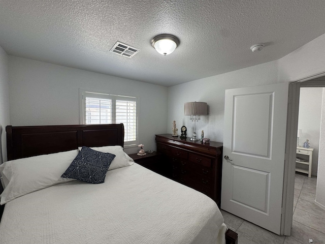 bedroom with light tile patterned floors, visible vents, and a textured ceiling