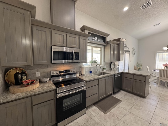 kitchen featuring tasteful backsplash, visible vents, a peninsula, stainless steel appliances, and a sink