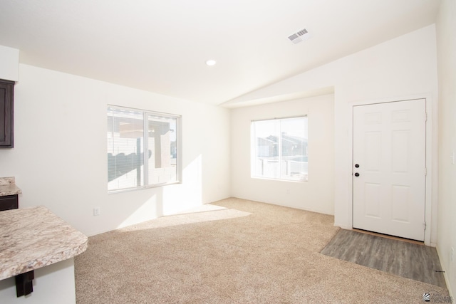 carpeted living room with plenty of natural light and vaulted ceiling