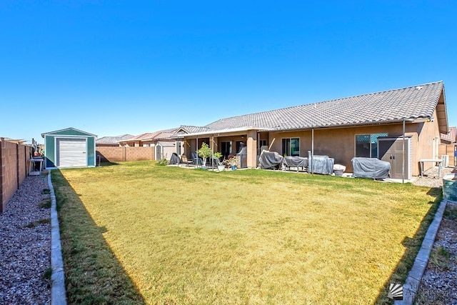 rear view of property with an outbuilding, a fenced backyard, a tile roof, a lawn, and stucco siding