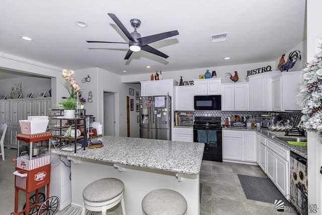 kitchen with a breakfast bar area, visible vents, decorative backsplash, white cabinets, and black appliances