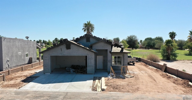 view of front of property with a garage, concrete driveway, stucco siding, and fence