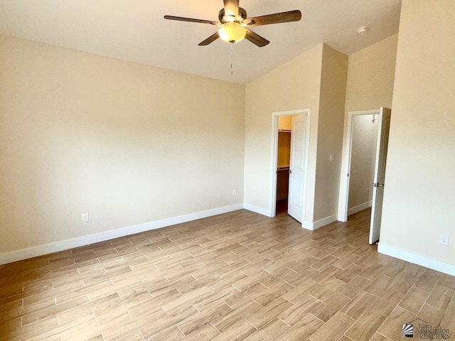 empty room featuring light wood-type flooring, baseboards, a ceiling fan, and vaulted ceiling