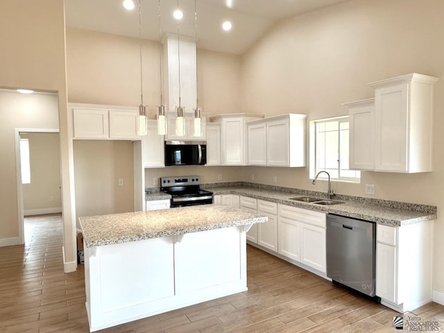 kitchen featuring high vaulted ceiling, a sink, a kitchen island, appliances with stainless steel finishes, and white cabinets