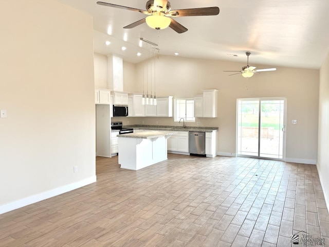 kitchen with light wood-style flooring, a kitchen island, open floor plan, appliances with stainless steel finishes, and white cabinets