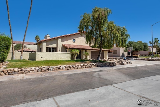 mediterranean / spanish-style home with a tiled roof, a garage, a chimney, fence, and stucco siding