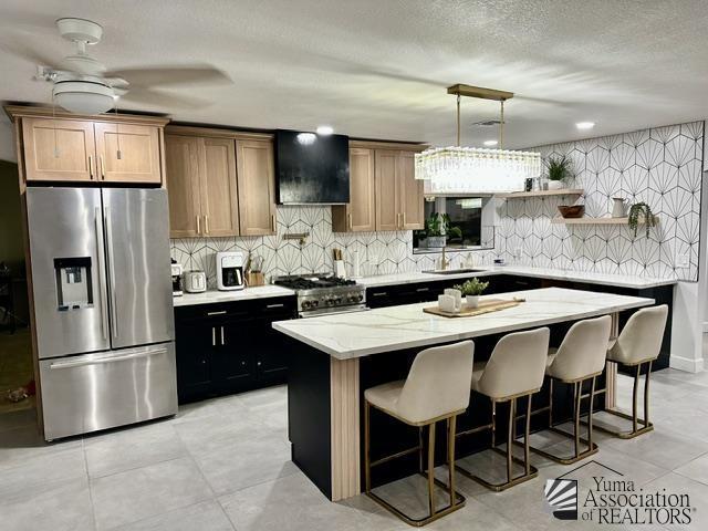 kitchen with appliances with stainless steel finishes, pendant lighting, sink, a breakfast bar area, and a center island