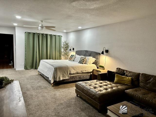 carpeted bedroom featuring ceiling fan and a textured ceiling