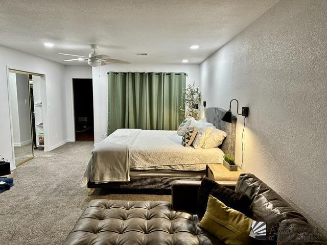 bedroom with ceiling fan, carpet floors, and a textured ceiling