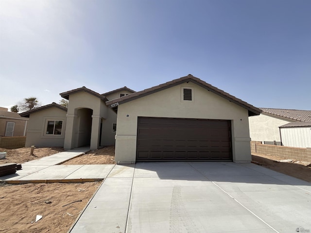 view of front of house with concrete driveway, a tile roof, an attached garage, and stucco siding