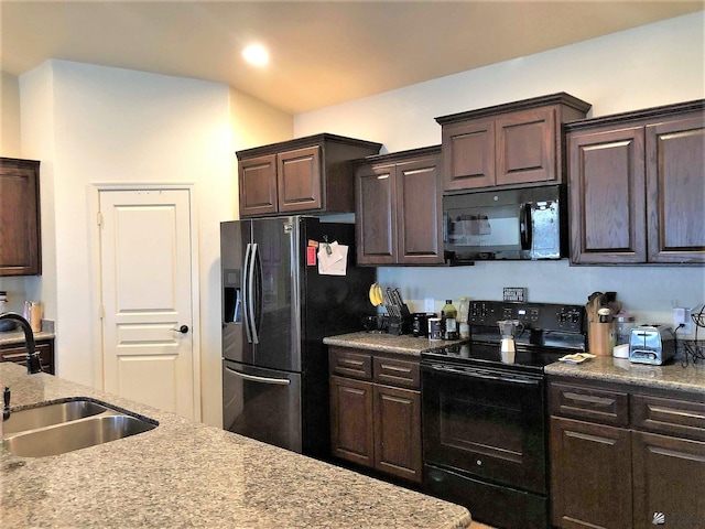 kitchen with light stone counters, dark brown cabinetry, sink, and black appliances