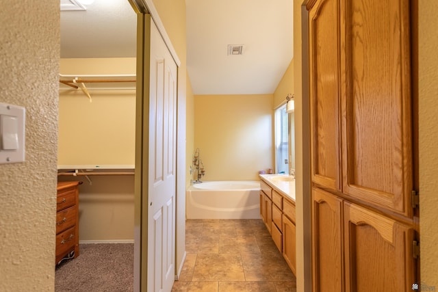 bathroom with vanity, a tub to relax in, and lofted ceiling