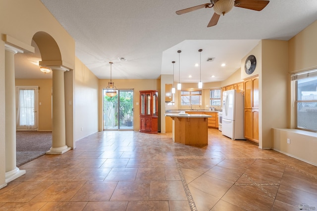 kitchen featuring white refrigerator, ceiling fan, decorative light fixtures, a kitchen island, and decorative columns