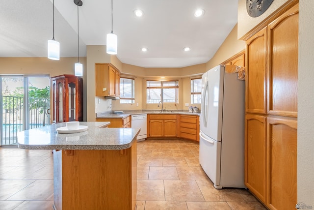 kitchen with white appliances, vaulted ceiling, sink, a kitchen island, and hanging light fixtures