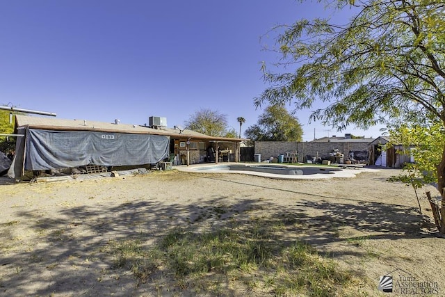 view of yard with central AC and a fenced in pool