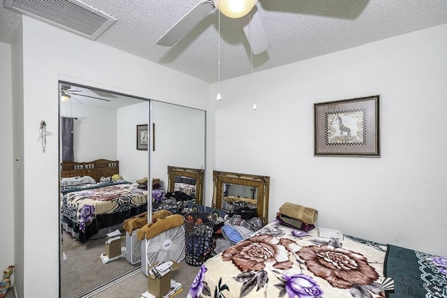 carpeted bedroom with ceiling fan, a closet, and a textured ceiling