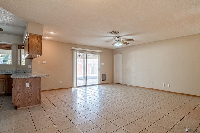 kitchen with a textured ceiling, light stone counters, ceiling fan, and light tile patterned flooring