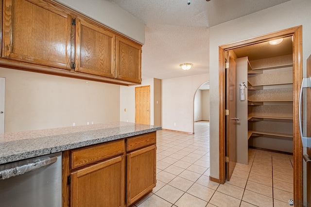 kitchen featuring dishwasher, light stone countertops, and light tile patterned floors