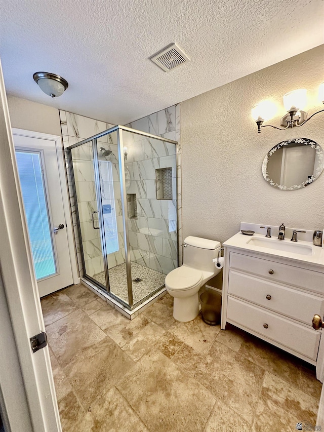 full bathroom featuring a textured wall, toilet, vanity, visible vents, and a stall shower