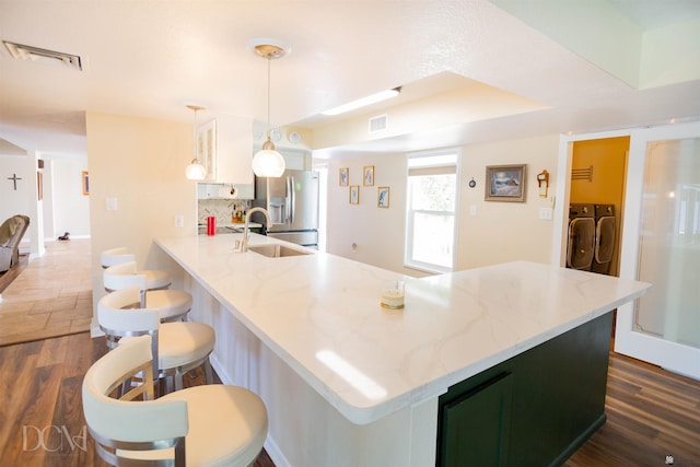 kitchen with visible vents, dark wood-style floors, independent washer and dryer, stainless steel refrigerator with ice dispenser, and a sink